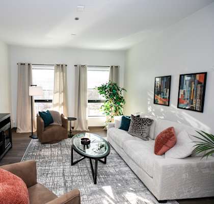 A living room with a white couch, a brown armchair, and a coffee table.