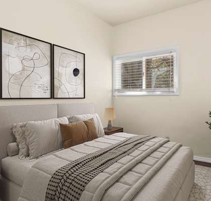 A bedroom with a large bed and a small tree.