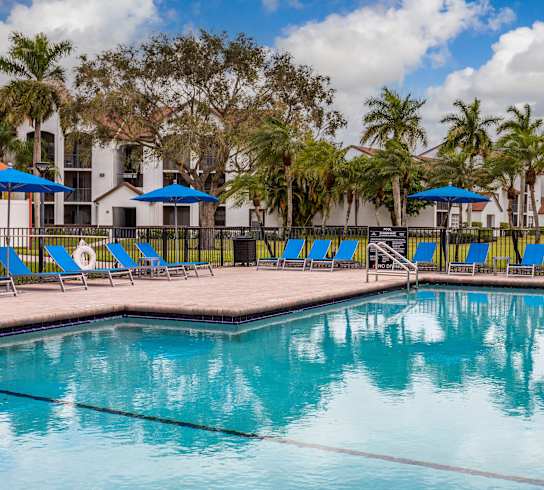 A pool with blue umbrellas and chairs.