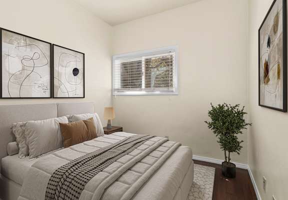 A bedroom with a bed, lamp, and artwork on the wall.