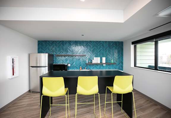 A kitchen with a black countertop and yellow chairs.