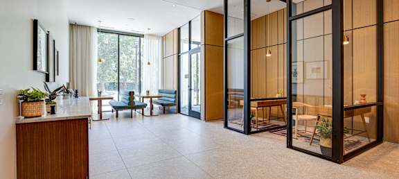 a lobby with glass walls and a table with a chair