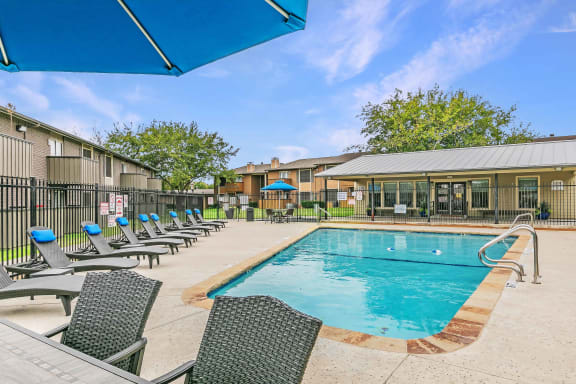 Resort-style pool with lounge chairs at Riata Park Apartments