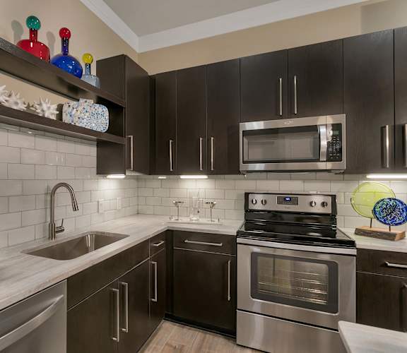 a kitchen with stainless steel appliances and black cabinets at Aster Apartments, Beachwood, OH 44122