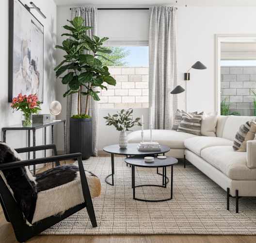 A living room with a white couch, a black chair, and a ceiling fan.
