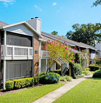 a brick apartment building with a porch and a sidewalk