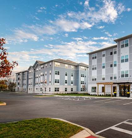 A large apartment complex with a parking lot in front.