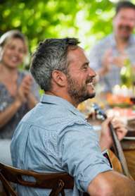 A man is playing guitar for a group of people at a table.