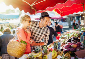 A man and a woman are shopping for fruits at a market.