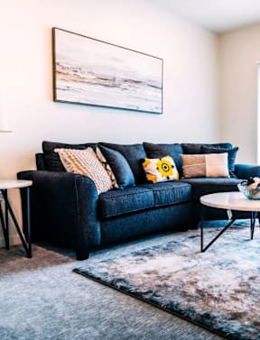 A living room with a dark blue couch and a white table.