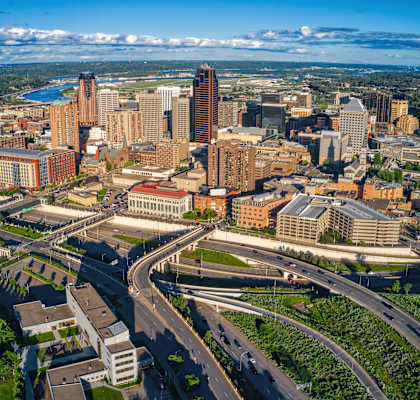 A cityscape with a mix of modern and older buildings, surrounded by greenery and roads.