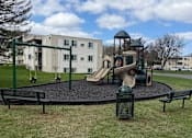 Thumbnail 35 of 38 - A playground with a slide, swings, and a seesaw.