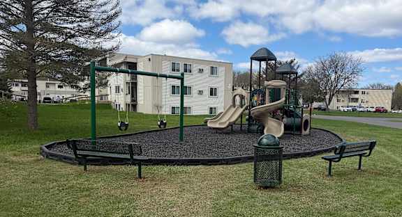 A playground with a slide, swings, and a seesaw.
