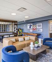 A blue chair sits in a room with a tan couch and a coffee table. at 360 State Street, New Haven, CT, 06510