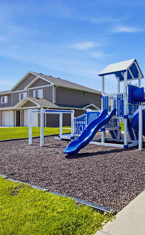 A playground with a blue slide and a green bench.