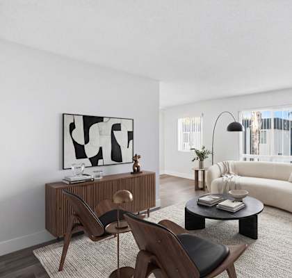 A living room with a white sofa, a wooden chair, a coffee table, and a plant.