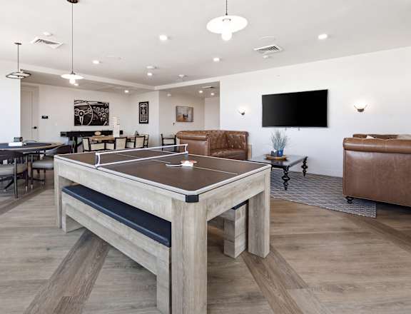 A ping pong table is in the middle of a room with a couch and a TV.