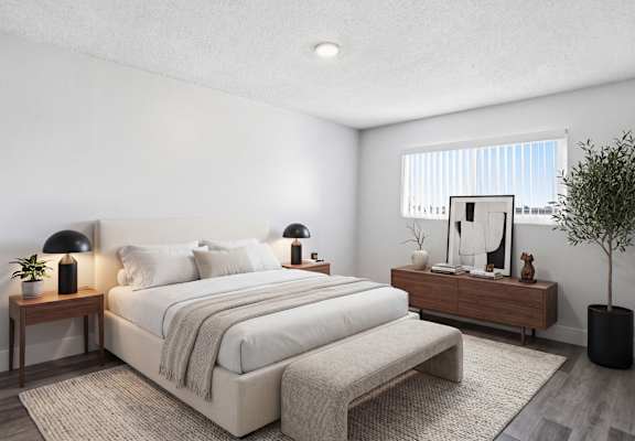 A well-lit bedroom with a large bed and a small tree.