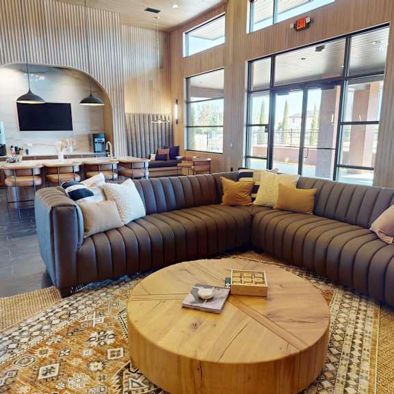 A living room with a large couch and a TV mounted on the wall.