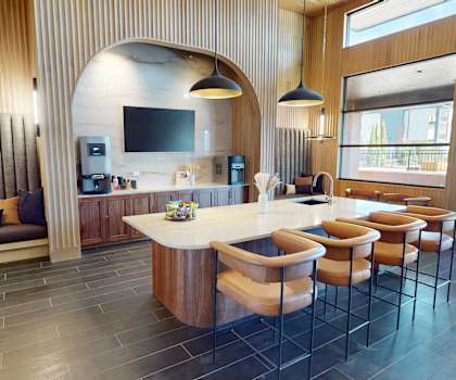 A modern kitchen with a long island and chairs.