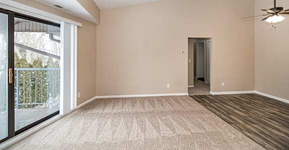 A room with a carpeted floor and a ceiling fan.