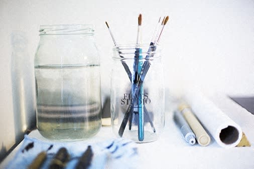 a group of toothbrushes in a glass jar on a shelf