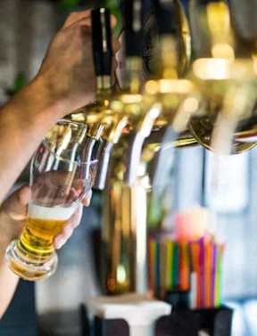 A person is pouring a golden liquid into a glass.