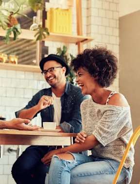 A man and a woman are sitting at a table, laughing together.