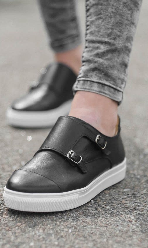 a close up of a person wearing a black shoe on the street