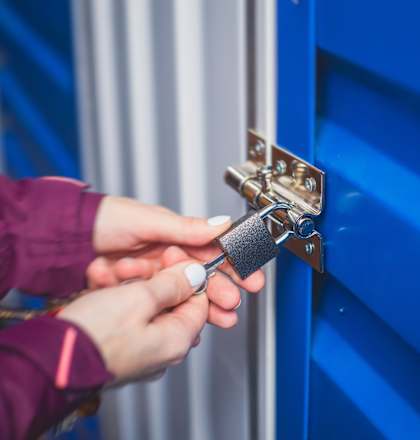 A person is opening a blue door with a key.
