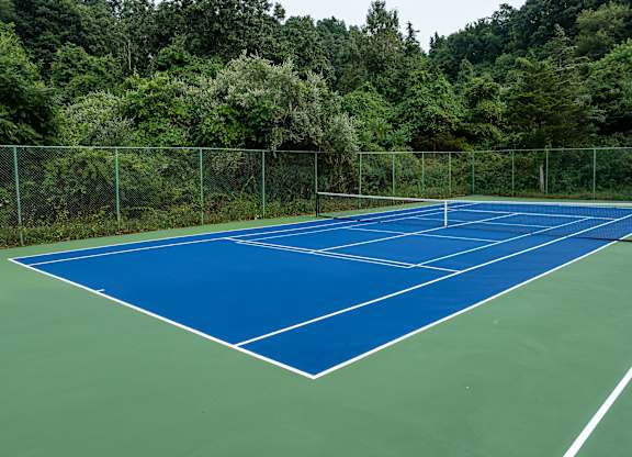 A tennis court surrounded by a green fence.