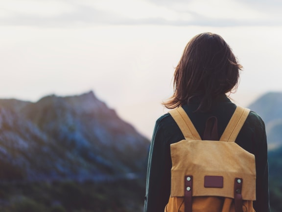 a woman with a backpack standing on top of a mountain