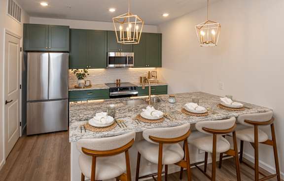 A kitchen with a marble countertop and a bar area with stools.