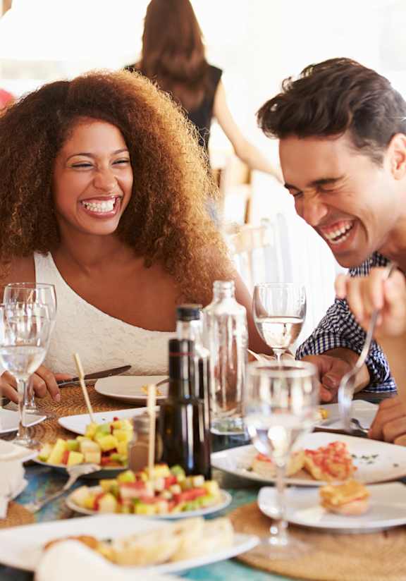 A group of people are sitting around a table enjoying a meal together.