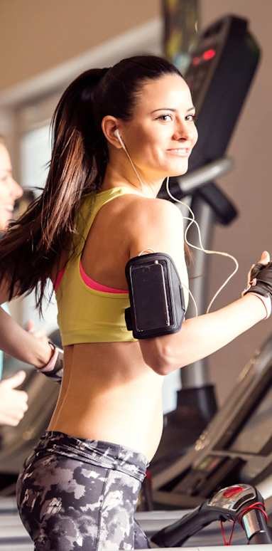 A woman in a yellow top and camouflage pants is using a treadmill.