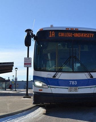 a blue and white bus parked at a bus stop