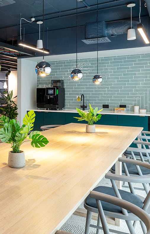 a large wooden table in a restaurant with blue tiles and chairs