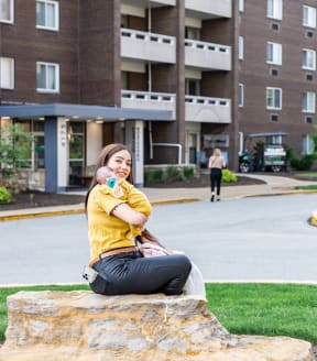a woman sitting on a rock in front of an apartment building