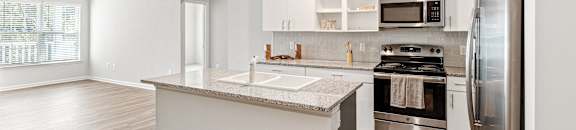 a renovated kitchen with stainless steel appliances and white cabinets at The Met Apartment Homes, Hattiesburg, 39402