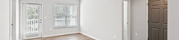 an empty living room with wood flooring and a brown door at The Met Apartment Homes, Hattiesburg, 39402