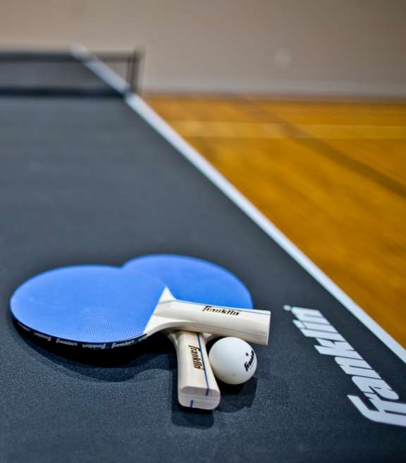 A ping pong paddle and ball are on a ping pong table.