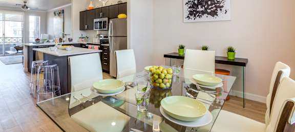 A modern dining room with a glass table and white chairs.