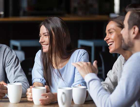 a group of people sitting at a table drinking coffee
