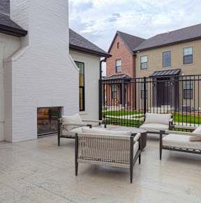 A patio with a table and chairs is in front of a brick building.