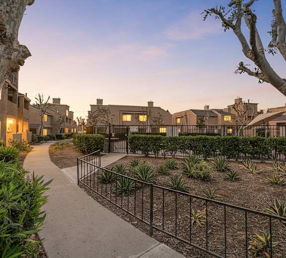 A residential area with a sidewalk and a fence.