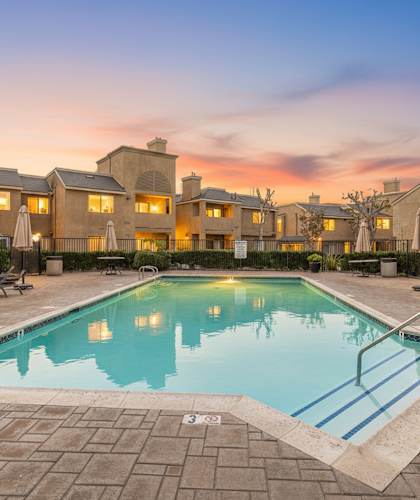 A swimming pool surrounded by a brick patio and lounge chairs.