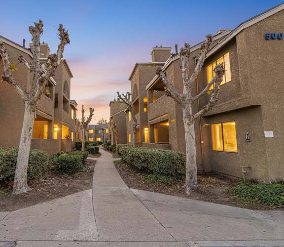 A row of apartment buildings with trees in front of them.