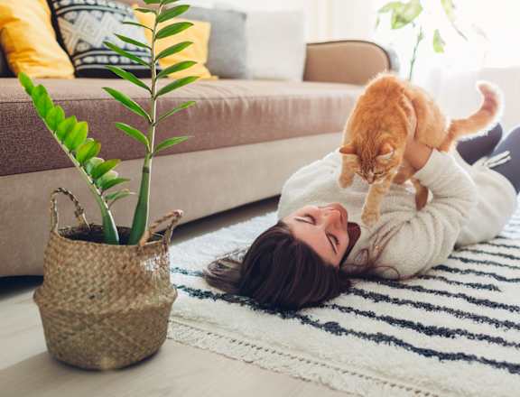 a woman laying on the floor with a cat on her head