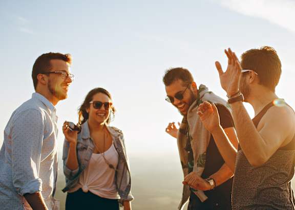 Four friends are standing together and enjoying the sunset.