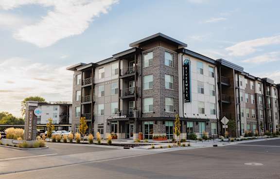 A modern apartment building with a parking lot in front.
